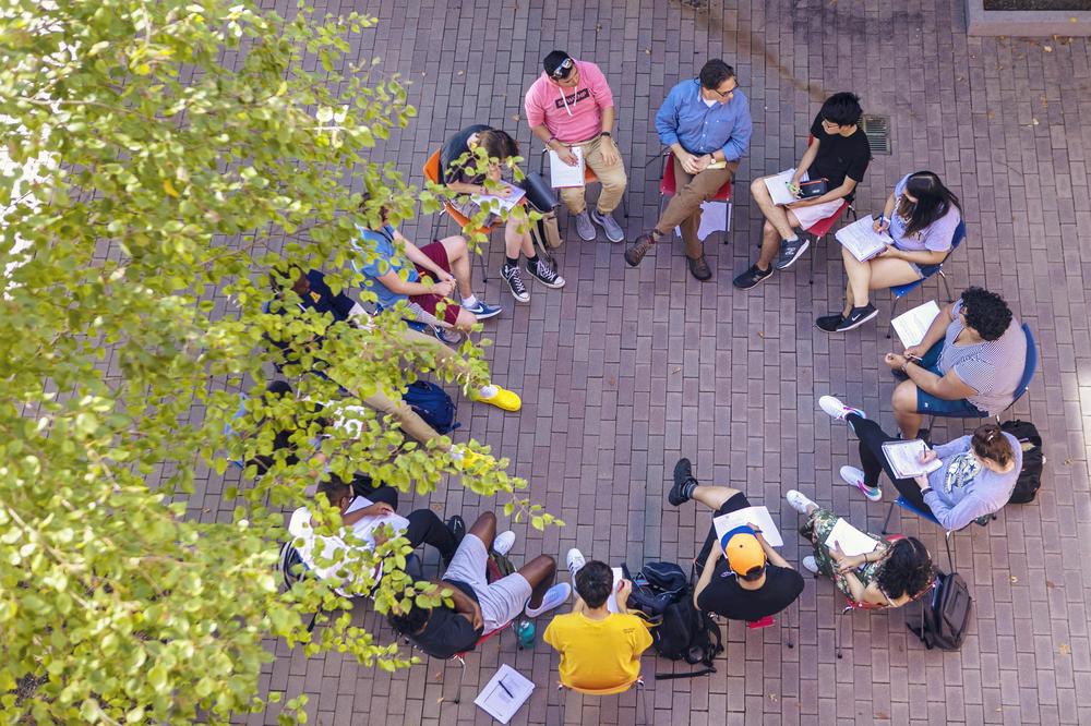 circle of students and a professor meeting outside, view from above